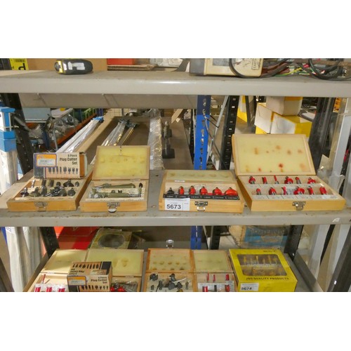 5673 - A quantity of various router bits and an 8 piece plug cutter set. Contents of 1 shelf