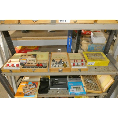 5674 - A quantity of various router bits and an 8 piece plug cutter set. Contents of 1 shelf