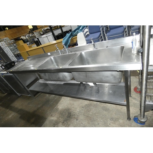 1207 - A commercial stainless steel deep double sink unit with draining board to the left approx 240x60cm