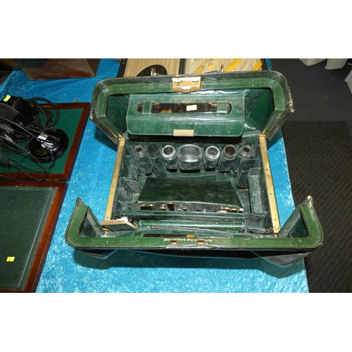 3088 - Two vintage green leather vanity cases each partly fitted to the interior