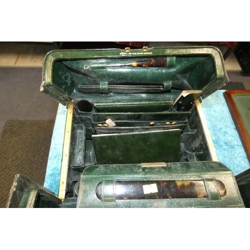 3088 - Two vintage green leather vanity cases each partly fitted to the interior