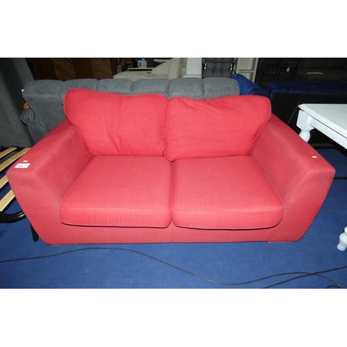 643 - A red upholstered two person sofa (no make visible). Please note this sofa is used and shows light s... 