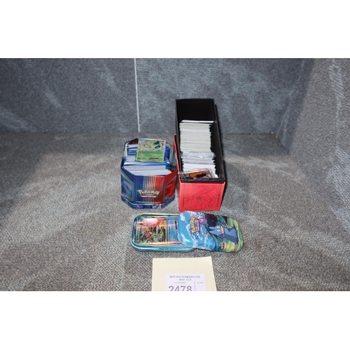 2478 - A trainer box and 2 tins containing a quantity of various collectible Pokémon trading cards