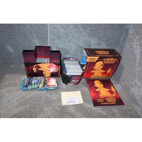 2479 - A trainer box and 2 tins containing a quantity of various collectible Pokémon trading cards