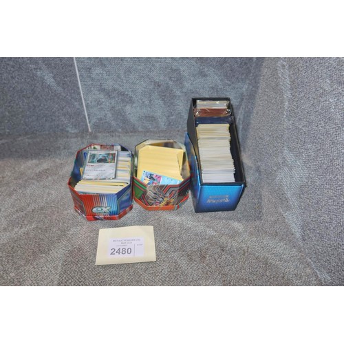 2480 - A trainer box and 2 tins containing a quantity of various collectible Pokémon trading cards