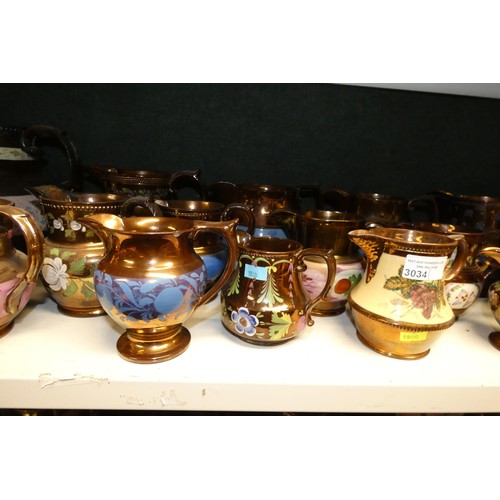 3034 - A large quantity of miscellaneous decorative bronze lustre jugs, tankards and goblets etc (two shelv... 