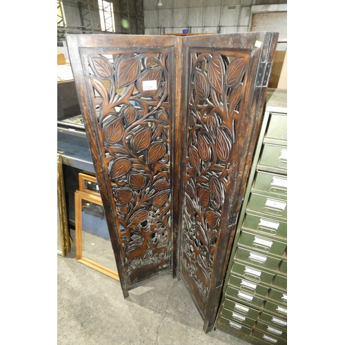 A heavily carved dark wood four fold modesty screen