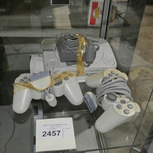 2457 - A Playstation 1 slim console and 2 controllers