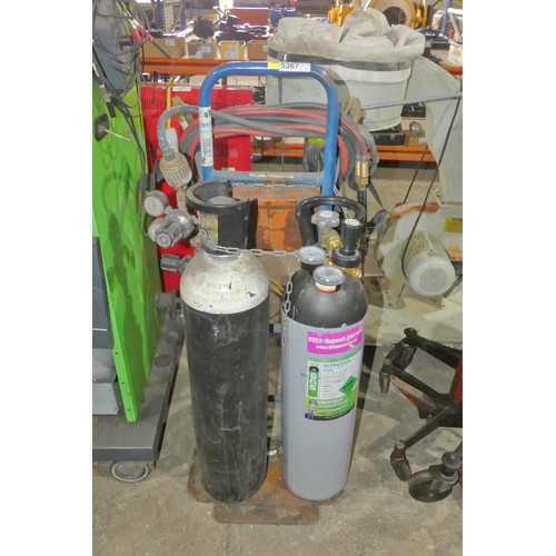 5367 - A twin gas bottle trolley with hose, gauges and a cutting torch. Please note the two gas bottles sho... 