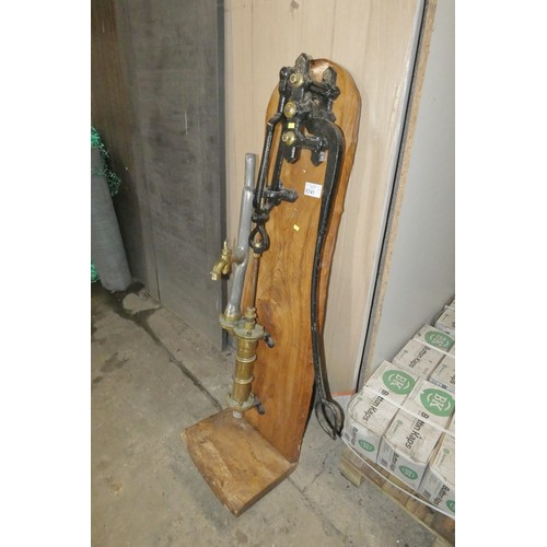 5741 - A vintage ornamental brass and lead hand pump mounted on a wooden board - can be made to pump water