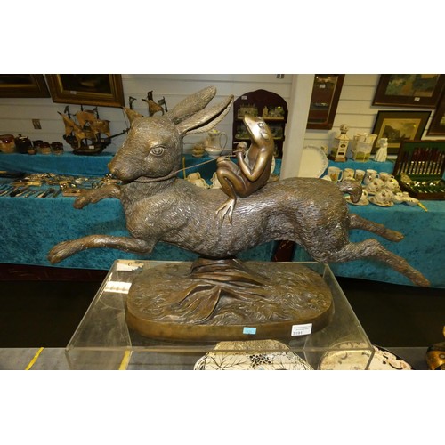 A large heavy bronze coloured cast metal figure of a frog riding a rabbit