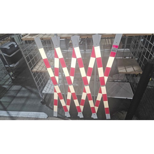 3373 - A red / white plastic folding barrier with a two part metal stand. Please note that one of the brack... 