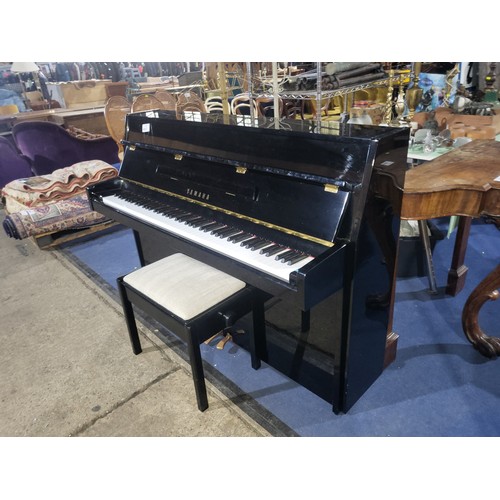A modern compact upright Yamaha M108 Piano in a high gloss black case with matching adjustable piano