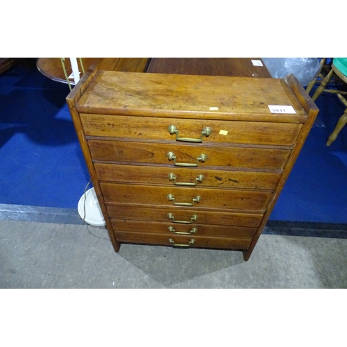 3411 - A vintage golden oak floor standing chest of seven small drawers with brass drop handles, approximat... 
