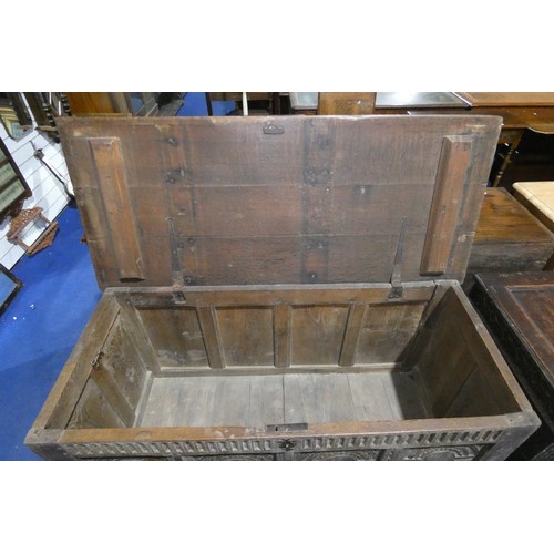 7404 - An early heavily carved oak coffer with a lift lid and a four panelled front, approximately 142 cm w... 