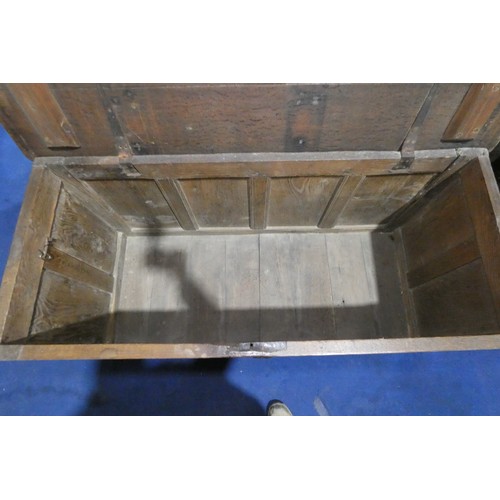 7404 - An early heavily carved oak coffer with a lift lid and a four panelled front, approximately 142 cm w... 