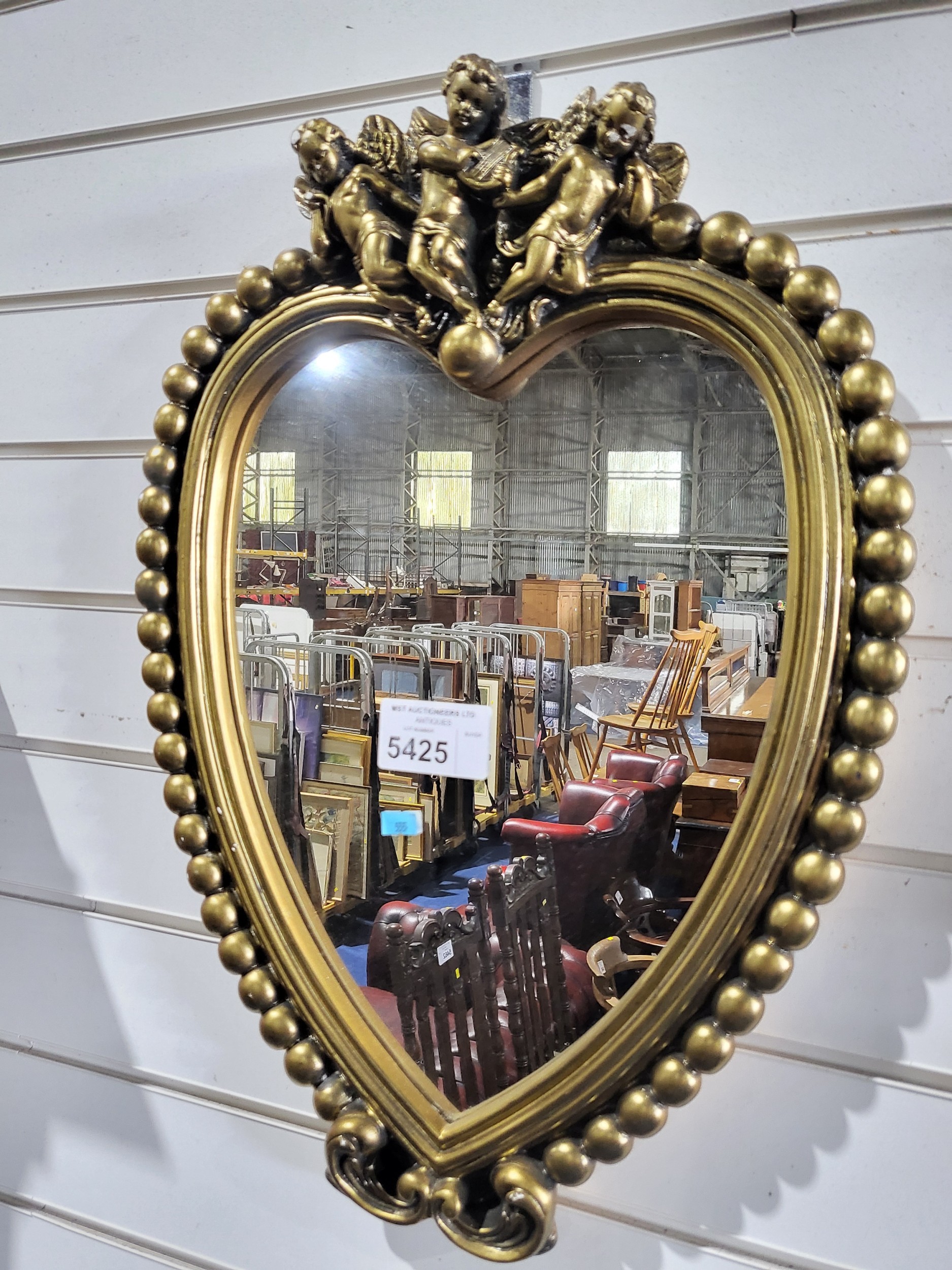 A Vintage Gilt Heart shaped hall mirror with cupids above a bobbin frame.