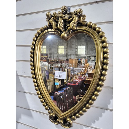 A Vintage Gilt Heart shaped hall mirror with cupids above a bobbin frame.