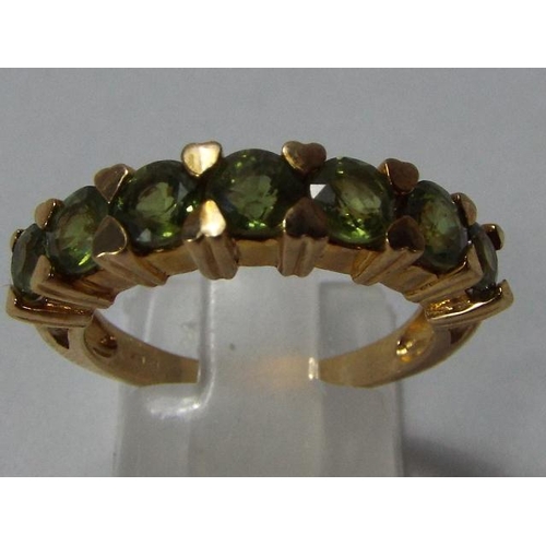 130 - 9ct yellow gold 7 green sapphire ring. Size N/O. Weight: 4.08g