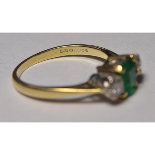 113 - 18ct gold engagement ring set with table cut emerald flanked by twin diamonds, stamped 750, hallmark... 