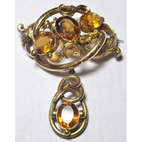 131 - Yellow metal pinchbeck brooch set with faceted citrine stones with scrolling design arms. 6cm wide 8... 