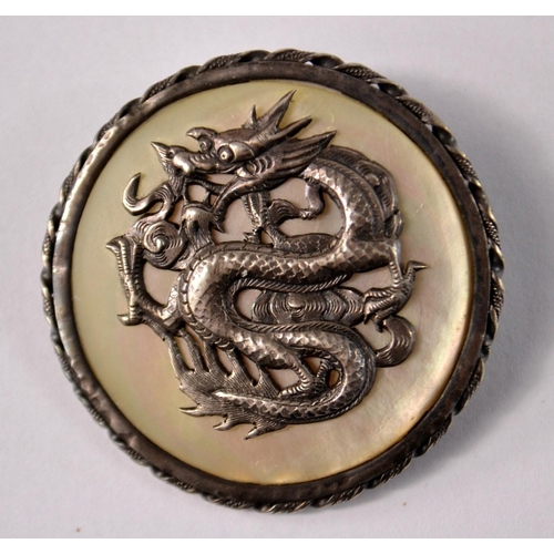 37 - A Chinese inspired white metal brooch, with a dragon on mother of pearl base. Has a clasp to secure ... 