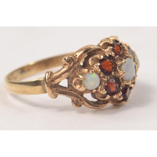 58 - 9ct Opal and garnet set ring. 3 Opals circled by 6 garnets in a floral design. Size N