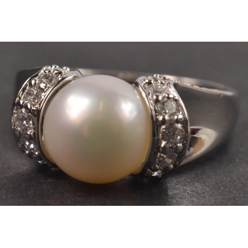 45 - 925 Silver stamped ring set with central pearl style stone and clear stone shoulders Size Q