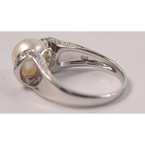 45 - 925 Silver stamped ring set with central pearl style stone and clear stone shoulders Size Q