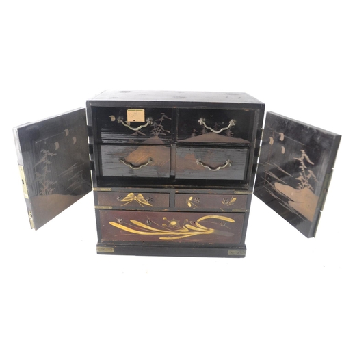 185 - An Oriental inspired brown & gold lacquered mini small cabinet with two doors, and 6 drawers