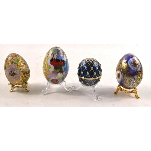 45 - Three highly decorative ceramic eggs on stands with A FABERGE inspired Jewel ENCRUSTED SMALL LIDDED ... 