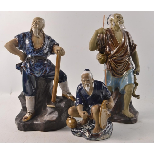 23G - A collection of three 'Chinese Mudmen' taller of the three 24cm tall, one rod missing from the crouc... 