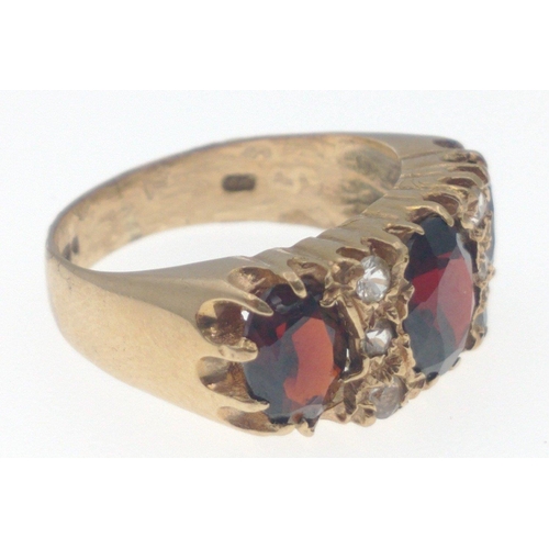 20 - A SUBSTANTIAL 375 stamped yellow gold ring set with a trio of garnets setting ring size N, weight gr... 