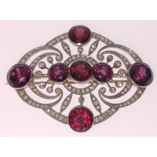 51 - ORNATE STUNNING ART DECO DESIGN! An unmarked diamond and garnet set BROOCH, with 7 round faceted gar... 