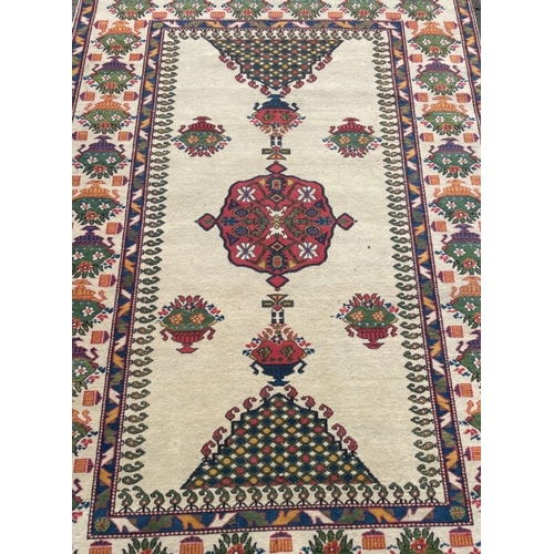 176 - A VINTAGE HANDMADE TRADITIONAL INDIAN CARPET with a creamy coloured background with urns of floral d... 