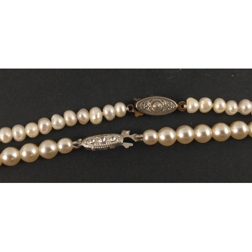 24 - TWO STRINGS OF REAL PEARLSA nice string of real PEARLS with white metal clasp with three small white... 