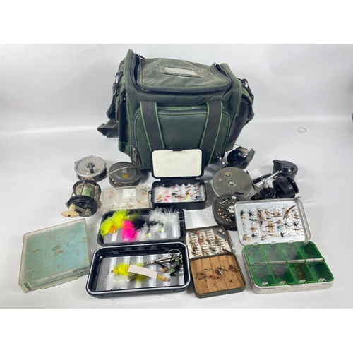 409 - A box of fishing paraphernalia to include 2 fishing bags with several reels including a MORRITTS INT... 