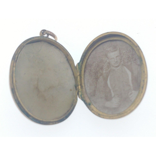 25 - Unmarked 'yellow metal' (jeweller tested 9ct) oval locket with metal liners -there is damage (a tear... 