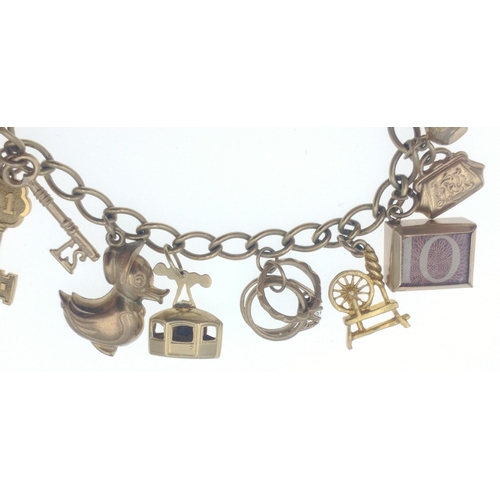 20 - A LOVELY 375 stamped yellow gold locket and charm bracelet FULL OF GOLD CHARMS, to include a safe, a... 