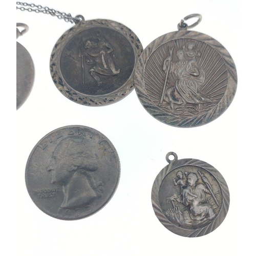 36 - Four silver stamped St Christopher pendants (1.5 - 3cm dia) also with a silver stamped disc, a 1973 ... 