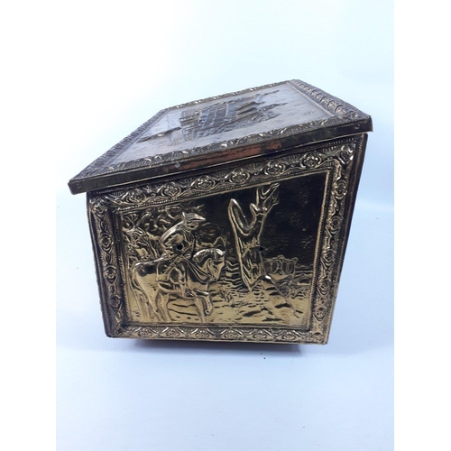 424 - A brass metal covered wooden fireside wood box with repousse design on lid and three sides of a Tudo... 