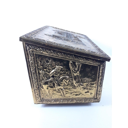 424 - A brass metal covered wooden fireside wood box with repousse design on lid and three sides of a Tudo... 