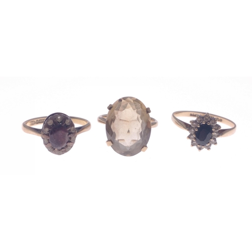 10 - A trio collection of 375 stamped yellow gold rings to include a smoky quartz centred ring size J, al... 