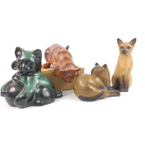 153 - A group of four cat figures in various media including a curled up wooden cat (10cm high), a North L... 