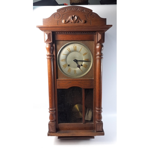 151 - A wooden wall clock with loose pendulum spring and key.  Minor issues to face.  No makers mark appar... 