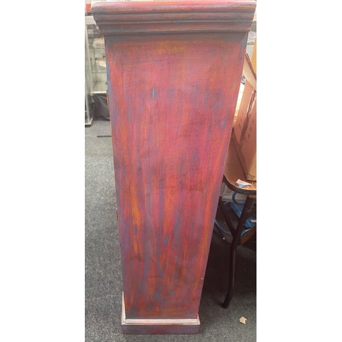 579 - A carved Indian cupboard with 3 internal shelves in coral pink with blue accents on the front, measu... 