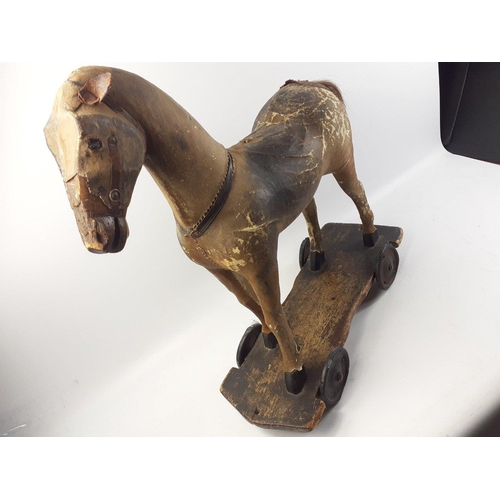 114 - A much-loved Victorian pull along horse made of leather over wood on a wheeled base.  This item is i... 