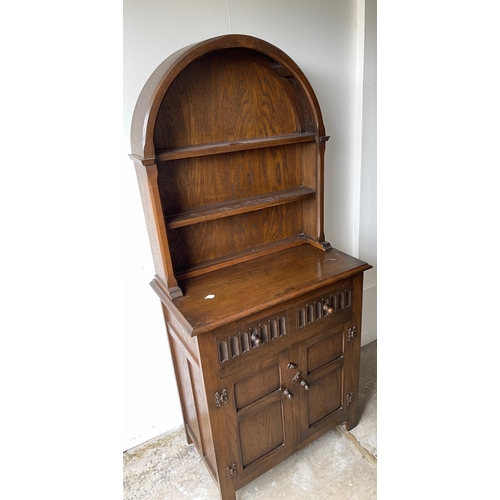 813 - An ERCOL inspired small dresser in dark oak with a semi-circular hooded-plate rack with 2 drawers an... 