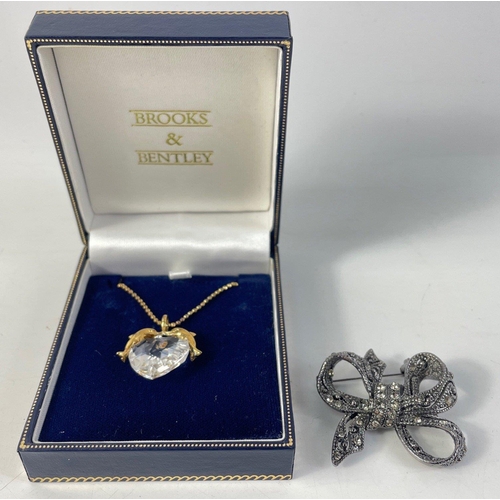 111 - A BROOKS & BENTLEY pendant with a clear heart-shaped stone held by a pair of dolphins, and chain... 