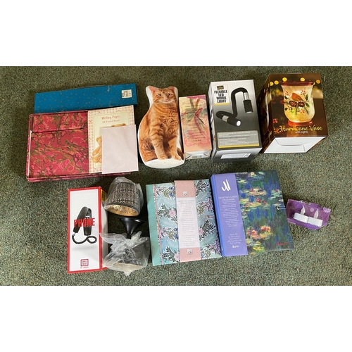 673 - A mixed lot all unused of writing paper packs, flexible LED light, a hurricane vase with lights, a g... 